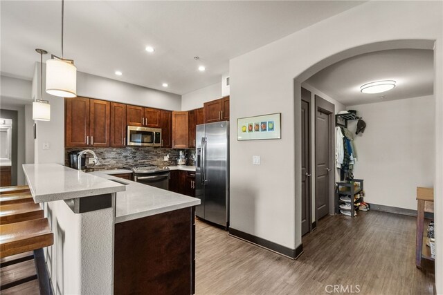24585 Town Center Dr Unit 4308, Valencia, CA 91355 - kitchen featuring stainless steel appliances, a peninsula, arched walkways, baseboards, and a sink