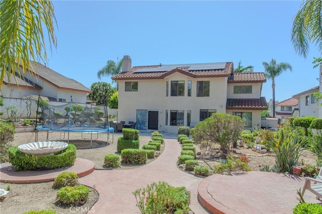 824 Leyland Dr, Diamond Bar, CA 91765 - rear view of property featuring a trampoline, stucco siding, roof mounted solar panels, and a chimney