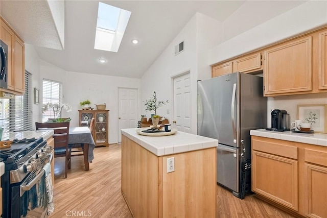 143 Brisas St, Oceanside, CA 92058 - kitchen with appliances with stainless steel finishes, tile countertops, a skylight, vaulted ceiling, and light wood-style floors