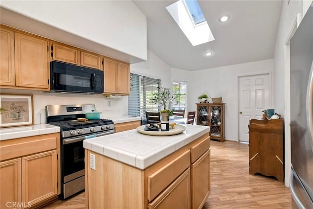 143 Brisas St, Oceanside, CA 92058 - kitchen with appliances with stainless steel finishes, tile countertops, a skylight, light wood finished floors, and recessed lighting