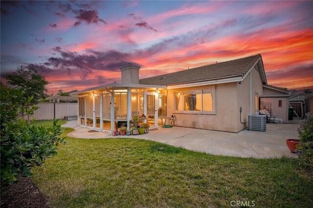 143 Brisas St, Oceanside, CA 92058 - back of property at dusk featuring a patio, central air condition unit, a sunroom, a chimney, and stucco siding
