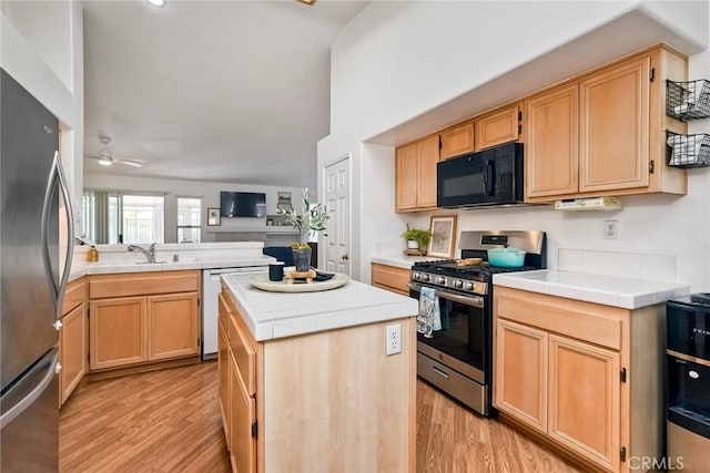 143 Brisas St, Oceanside, CA 92058 - kitchen with appliances with stainless steel finishes, tile counters, light wood finished floors, a kitchen island, and light brown cabinets