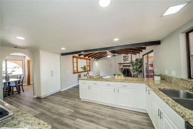 17470 Krameria Ave, Riverside, CA 92504 - kitchen featuring arched walkways, ceiling fan, a fireplace, a peninsula, and light wood-style floors