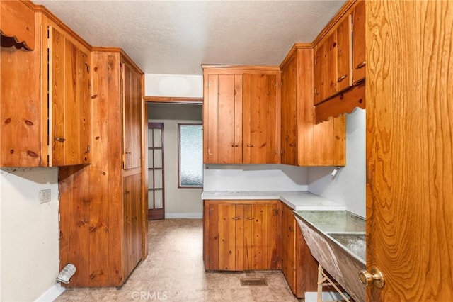 26972 State Highway 189, Blue Jay, CA 92317 - kitchen featuring baseboards, a textured ceiling, brown cabinetry, light countertops, and light flooring