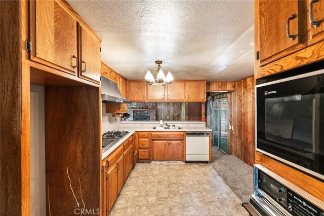 26972 State Highway 189, Blue Jay, CA 92317 - kitchen featuring dishwasher, under cabinet range hood, a chandelier, light countertops, and brown cabinetry