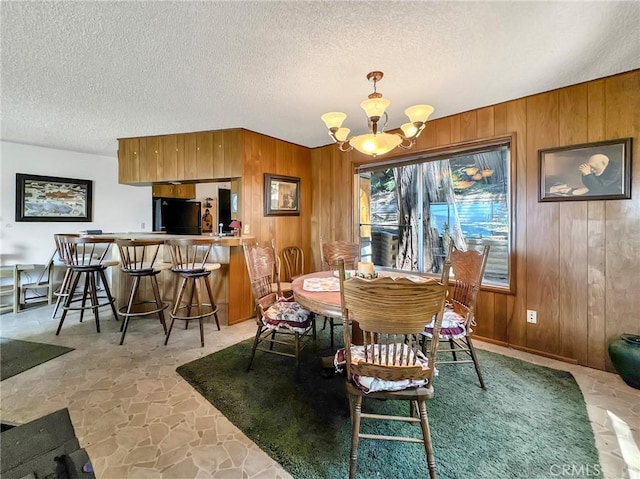 113 Fremont Rd, Lake Arrowhead, CA 92352 - dining room featuring a chandelier, wooden walls, stone floors, and a textured ceiling
