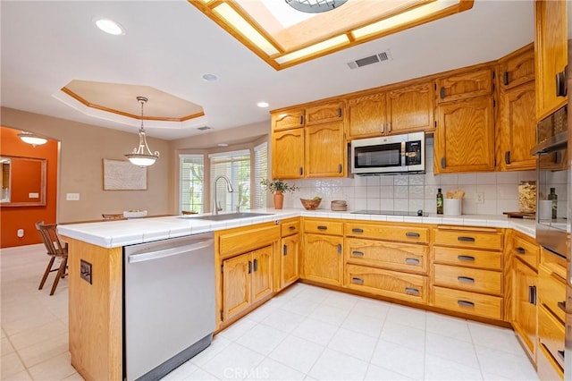 625 Redwing Dr, Merced, CA 95340 - kitchen featuring appliances with stainless steel finishes, a raised ceiling, a sink, backsplash, and a peninsula