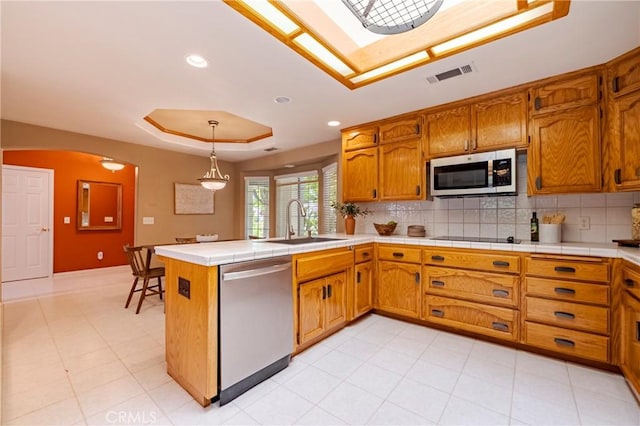 625 Redwing Dr, Merced, CA 95340 - kitchen featuring appliances with stainless steel finishes, a raised ceiling, a sink, brown cabinets, and arched walkways