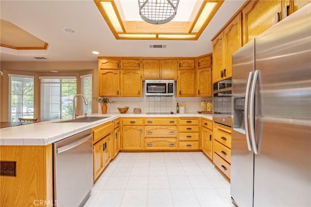 625 Redwing Dr, Merced, CA 95340 - kitchen with stainless steel appliances, a raised ceiling, a peninsula, a sink, and tasteful backsplash