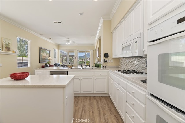 23463 Canterbury Way, Murrieta, CA 92562 - kitchen with white appliances, a peninsula, light wood-style floors, ornamental molding, and white cabinetry