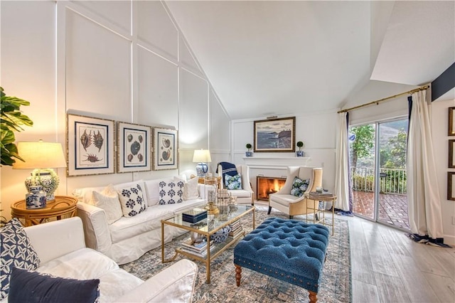 25536 Rue Terrase Unit 17, Laguna Niguel, CA 92677 - living area featuring vaulted ceiling, wood finished floors, a lit fireplace, and a decorative wall