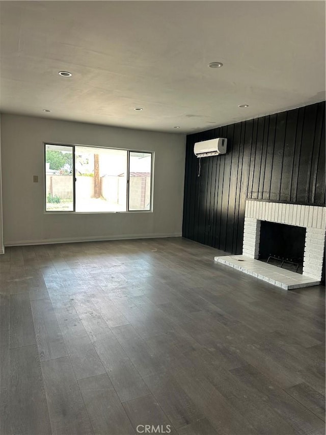45208 17th St W, Lancaster, CA 93534 - unfurnished living room with a wall mounted AC, a brick fireplace, wood finished floors, baseboards, and recessed lighting