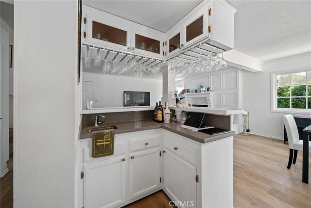 4420 Conchita Way, Tarzana, CA 91356 - kitchen with light wood finished floors, white cabinetry, glass insert cabinets, and a sink