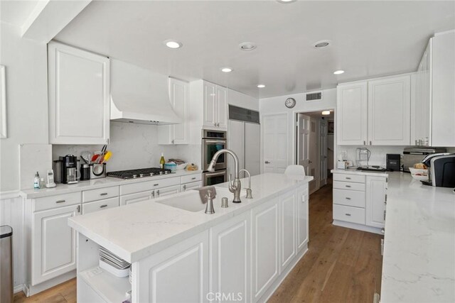 4420 Conchita Way, Tarzana, CA 91356 - kitchen featuring appliances with stainless steel finishes, custom range hood, white cabinetry, light wood finished floors, and recessed lighting