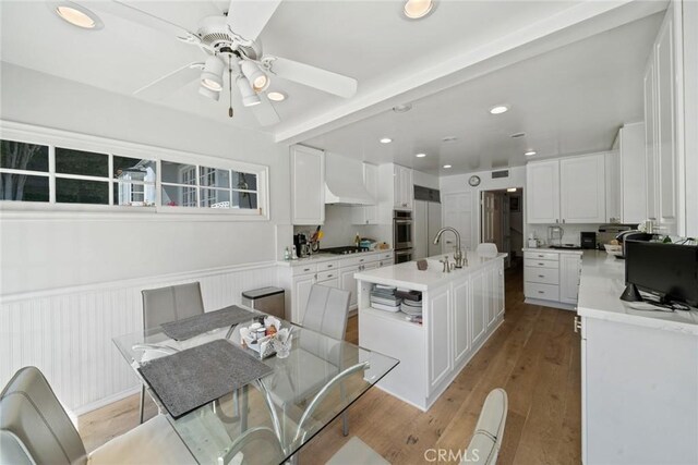 4420 Conchita Way, Tarzana, CA 91356 - kitchen featuring an island with sink, white cabinets, ceiling fan, light wood finished floors, and a wainscoted wall