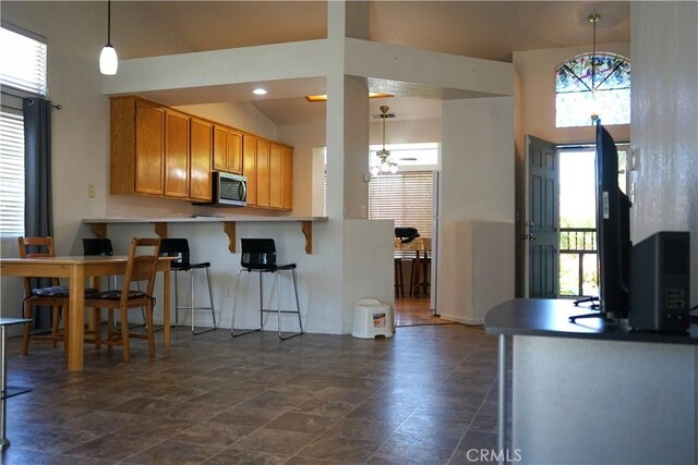2068 Spy Glass Ct, Merced, CA 95340 - kitchen featuring stainless steel microwave, a kitchen breakfast bar, pendant lighting, and brown cabinets