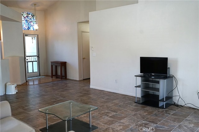 2068 Spy Glass Ct, Merced, CA 95340 - unfurnished living room featuring stone finish flooring, a towering ceiling, and baseboards