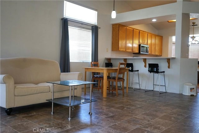 2068 Spy Glass Ct, Merced, CA 95340 - kitchen with stainless steel microwave, a breakfast bar, dark stone finish floors, a peninsula, and pendant lighting