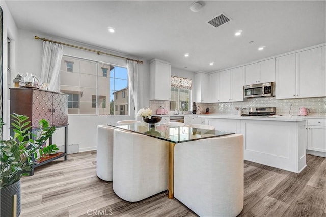 747 Spring Gdn, Irvine, CA 92618 - kitchen with appliances with stainless steel finishes, light wood-style flooring, decorative backsplash, white cabinetry, and recessed lighting