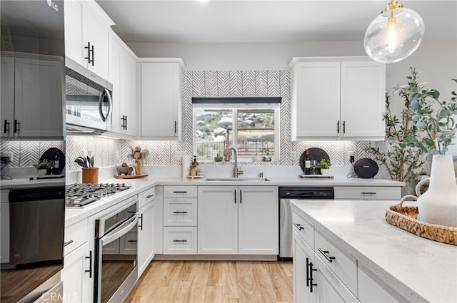 30893 Telegraph Dr, Winchester, CA 92596 - kitchen with stainless steel appliances, a sink, light wood-style flooring, white cabinetry, and decorative backsplash