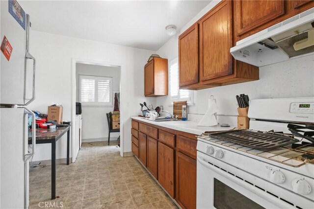 14508 Kingsdale Ave, Lawndale, CA 90260 - kitchen featuring white appliances, under cabinet range hood, healthy amount of natural light, and brown cabinets