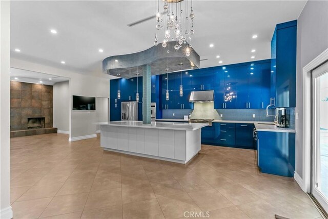 17206 Nugent Pl, Granada Hills, CA 91344 - kitchen with exhaust hood, blue cabinets, stainless steel fridge with ice dispenser, light countertops, and open floor plan