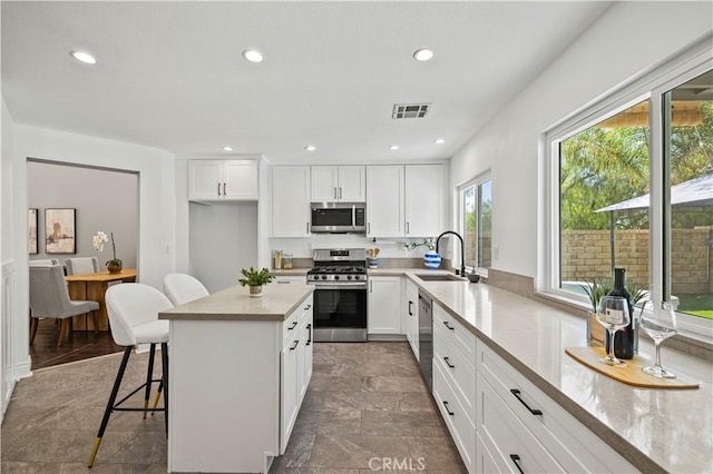27834 Lassen St, Castaic, CA 91384 - kitchen featuring stainless steel appliances, white cabinets, recessed lighting, a breakfast bar, and a center island