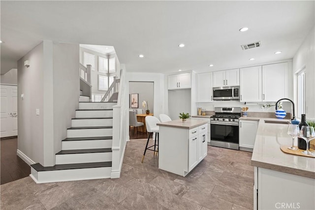 27834 Lassen St, Castaic, CA 91384 - kitchen with stainless steel appliances, white cabinets, a kitchen breakfast bar, a kitchen island, and recessed lighting