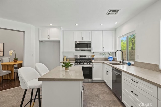 27834 Lassen St, Castaic, CA 91384 - kitchen with appliances with stainless steel finishes, white cabinetry, a kitchen island, and recessed lighting
