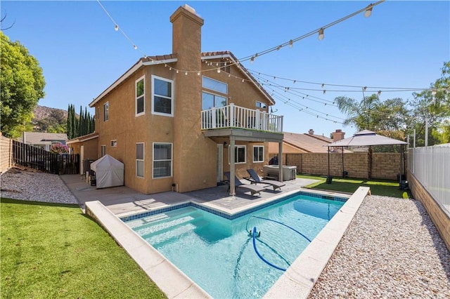 27834 Lassen St, Castaic, CA 91384 - back of property featuring a fenced backyard, a chimney, a patio area, stucco siding, and a balcony