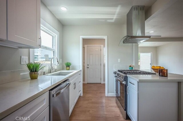 784 W 17th St, San Bernardino, CA 92405 - kitchen featuring stainless steel appliances, a sink, island range hood, light wood-style flooring, and light countertops