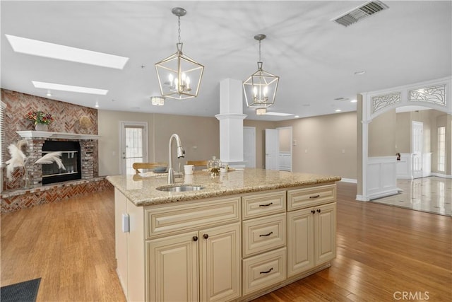 1641 Ford St, Redlands, CA 92373 - kitchen featuring a sink, open floor plan, cream cabinets, light wood-style flooring, and a fireplace