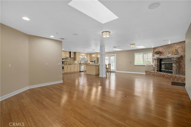 1641 Ford St, Redlands, CA 92373 - unfurnished living room featuring a large fireplace, wood finished floors, baseboards, a skylight, and recessed lighting