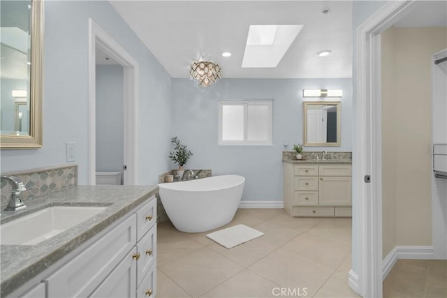 1641 Ford St, Redlands, CA 92373 - full bath featuring a skylight, a freestanding tub, two vanities, tile patterned floors, and baseboards