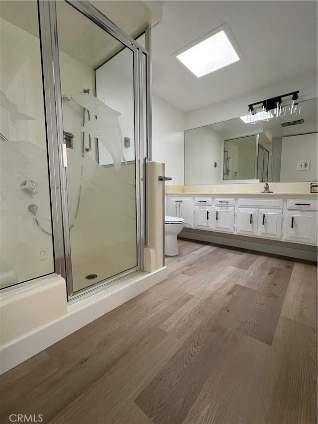 13962 El Dorado Dr Unit M2-60E, Seal Beach, CA 90740 - bathroom featuring toilet, wood finished floors, vanity, and a stall shower