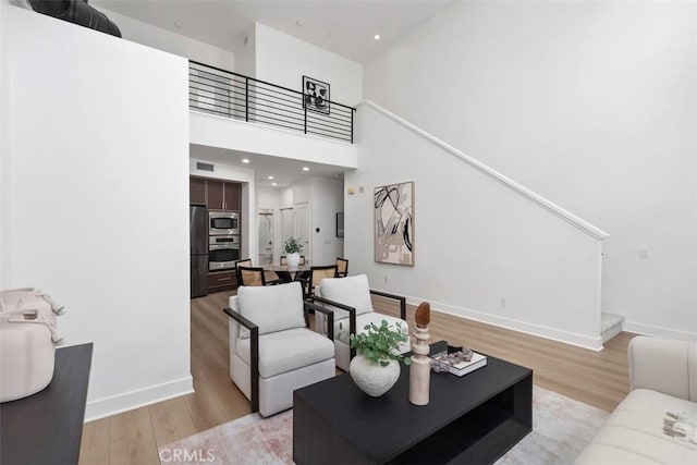 27 Delancy, Irvine, CA 92612 - living area with light wood-type flooring, stairway, a towering ceiling, baseboards, and recessed lighting
