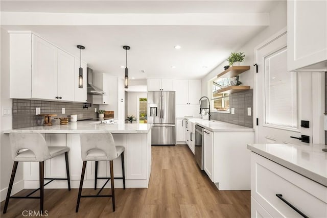 9802 Effingham Dr, Huntington Beach, CA 92646 - kitchen with appliances with stainless steel finishes, a peninsula, tasteful backsplash, white cabinets, and light wood-style floors