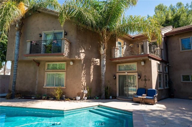 19162 Liggett St, Northridge, CA 91324 - back of house with a balcony, a patio area, an outdoor pool, and stucco siding
