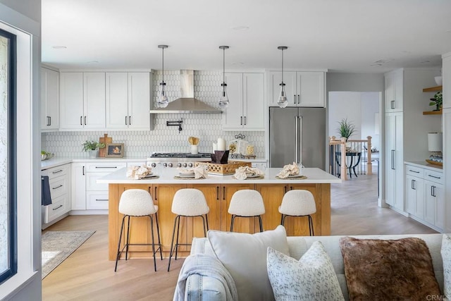 1051 Via Rancho Pkwy, Escondido, CA 92029 - kitchen with appliances with stainless steel finishes, wall chimney exhaust hood, backsplash, light wood-style flooring, and light countertops