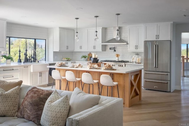 1051 Via Rancho Pkwy, Escondido, CA 92029 - kitchen with stainless steel appliances, open floor plan, wall chimney exhaust hood, light countertops, and decorative backsplash
