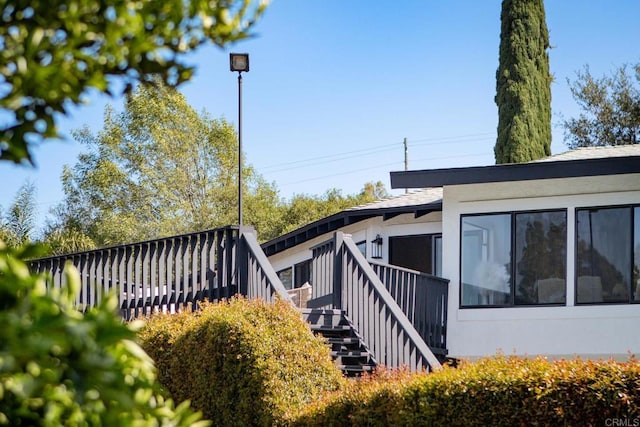 1051 Via Rancho Pkwy, Escondido, CA 92029 - view of property exterior featuring a wooden deck, stucco siding, and a sunroom