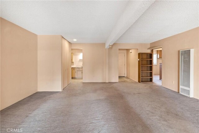 332 E 7th St, San Jacinto, CA 92583 - unfurnished living room with a heating unit, carpet, a textured ceiling, and beam ceiling