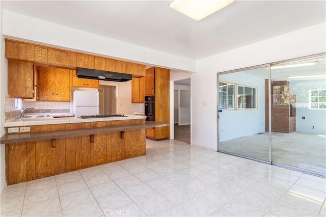 15903 Bryant St, North Hills, CA 91343 - kitchen with brown cabinetry, freestanding refrigerator, oven, a peninsula, and ventilation hood