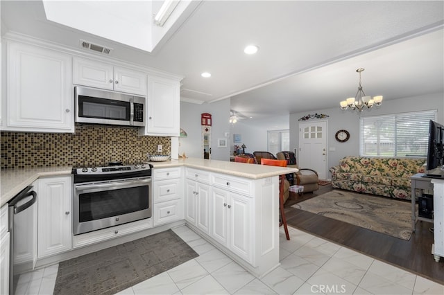 1420 Northwood Rd Unit 241C, Seal Beach, CA 90740 - kitchen with stainless steel appliances, open floor plan, a peninsula, light countertops, and white cabinetry