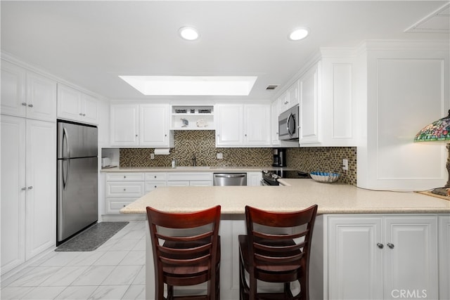 1420 Northwood Rd Unit 241C, Seal Beach, CA 90740 - kitchen with stainless steel appliances, white cabinetry, light countertops, a peninsula, and recessed lighting