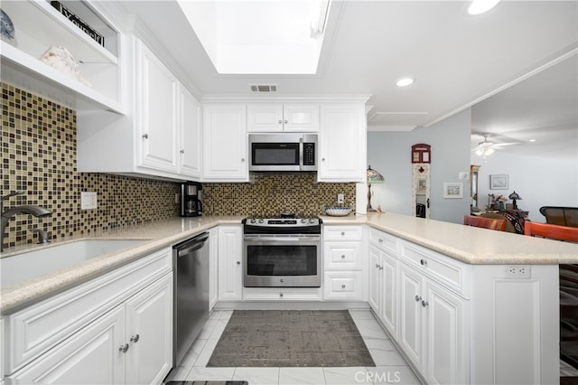 1420 Northwood Rd Unit 241C, Seal Beach, CA 90740 - kitchen with appliances with stainless steel finishes, a peninsula, tasteful backsplash, light countertops, and white cabinetry