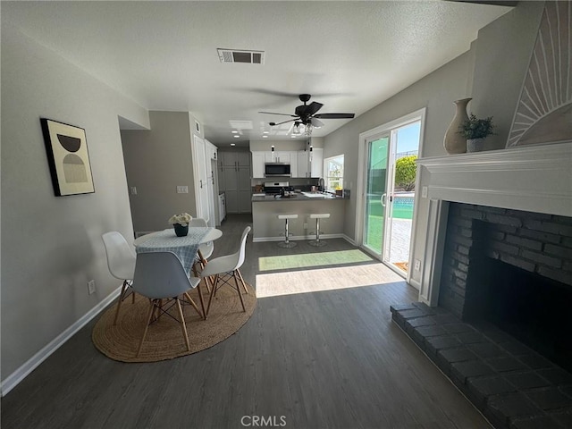 38422 Puma Ln, Palmdale, CA 93551 - dining space with dark wood finished floors, ceiling fan, baseboards, and a brick fireplace