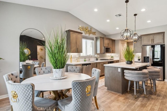 29589 Woodcreek Trl, Winchester, CA 92596 - kitchen with stainless steel appliances, a kitchen island, vaulted ceiling, light countertops, and light wood-style flooring