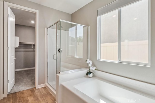 29589 Woodcreek Trl, Winchester, CA 92596 - bathroom featuring a shower stall, a bath, wood finished floors, a walk in closet, and baseboards