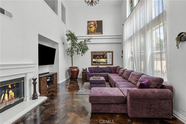 29259 Black Pine Way, Saugus, CA 91390 - living area with a towering ceiling, concrete flooring, a glass covered fireplace, baseboards, and a chandelier
